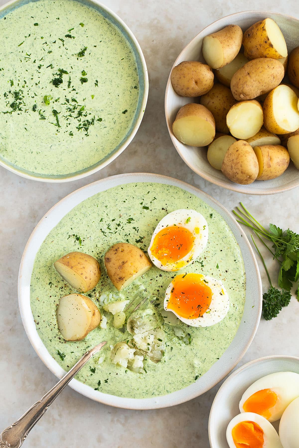 plate with frankfurter sauce, eggs and potatoes, other bowls with sauce, potatoes and eggs around it.