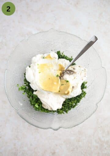 chopped herbs, sour cream, yogurt and mustard in a bowl for making green sauce.