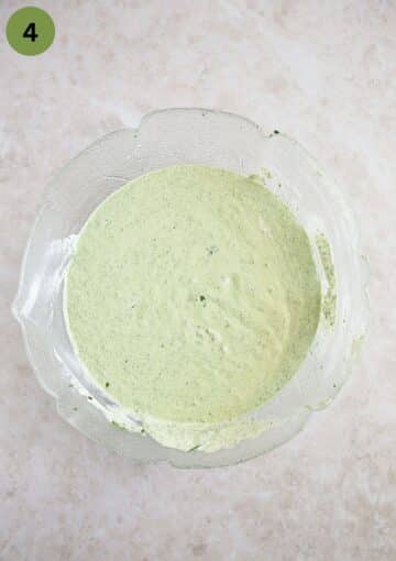 large bowl full of green sauce with yogurt and sour cream.