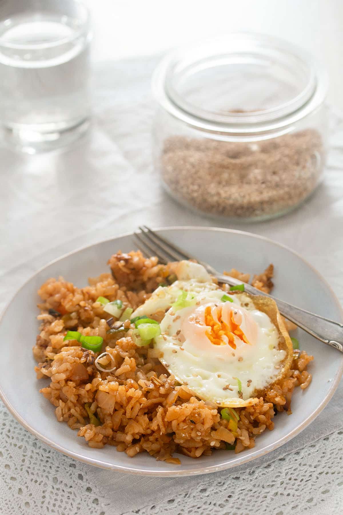 kimchi bacon fried rice with a fried egg on top on a plate.