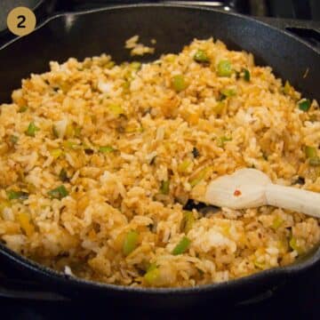 stirring fried rice with a wooden spoon in a skillet.