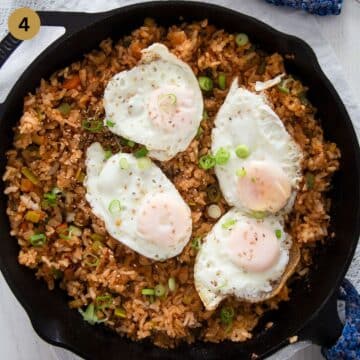 kimchi gochujang rice topped with four fried eggs in a skillet.