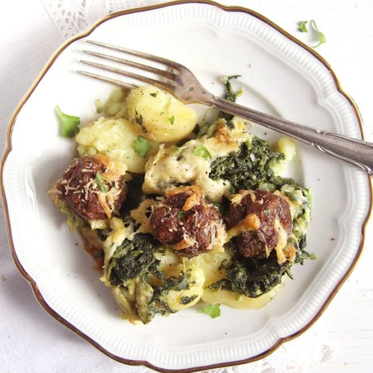 potato meatball casserole served on a small vintage plate with a silver fork on it.