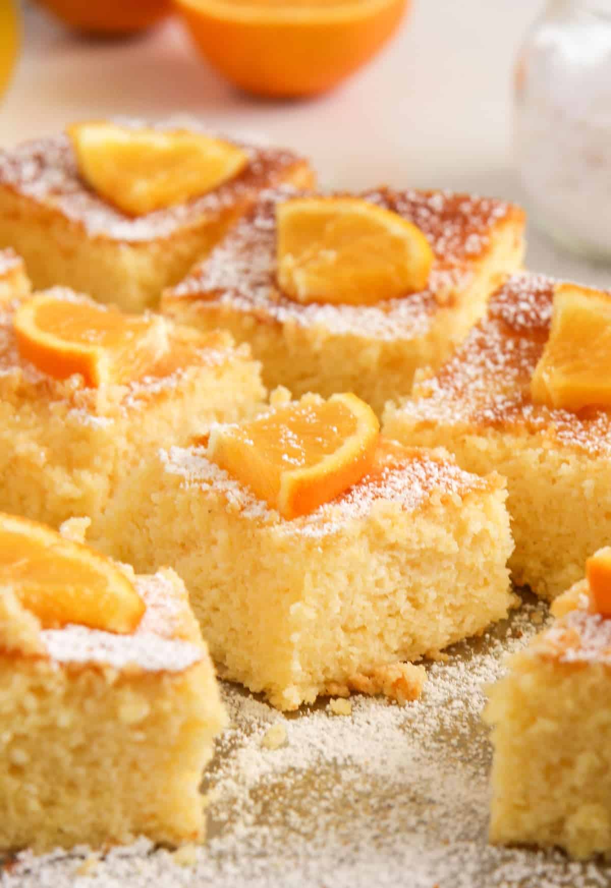 small cake pieces decorated with orange slicing and icing sugar.