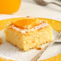 slice of polenta cake with orange syrup on a yellow plate with a fork.