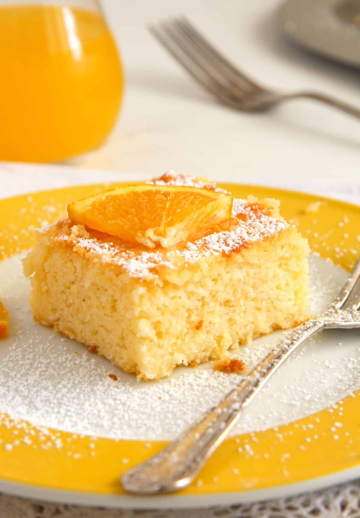 slice of polenta cake with orange syrup on a yellow plate with a fork.