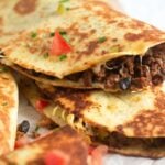 close up two groun beef quesadillas with black beans.