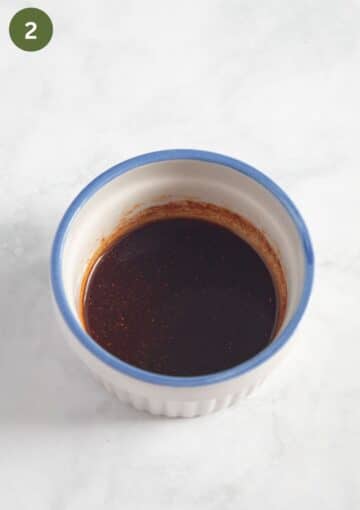 seasoning mixture with oil and paprika in a small bowl for roasting green onions.