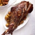 roasted leg of lamb with potatoes on a platter.