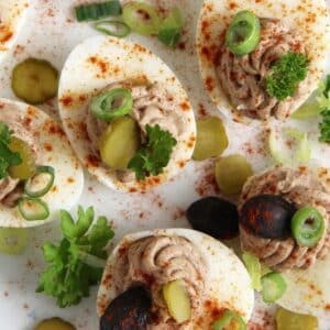 romanian deviled eggs filled with liver pate and garnished with olives and pickles.