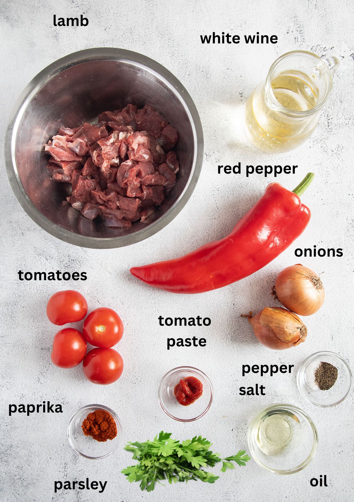 labeled ingredients for making romanian lamb stew with pepper, white wine, tomatoes, onions, parsley, and spices.