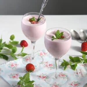 romanian strawberry foam or spuma de capsuni in two wine glasses decorated with mint and fresh strawberries.