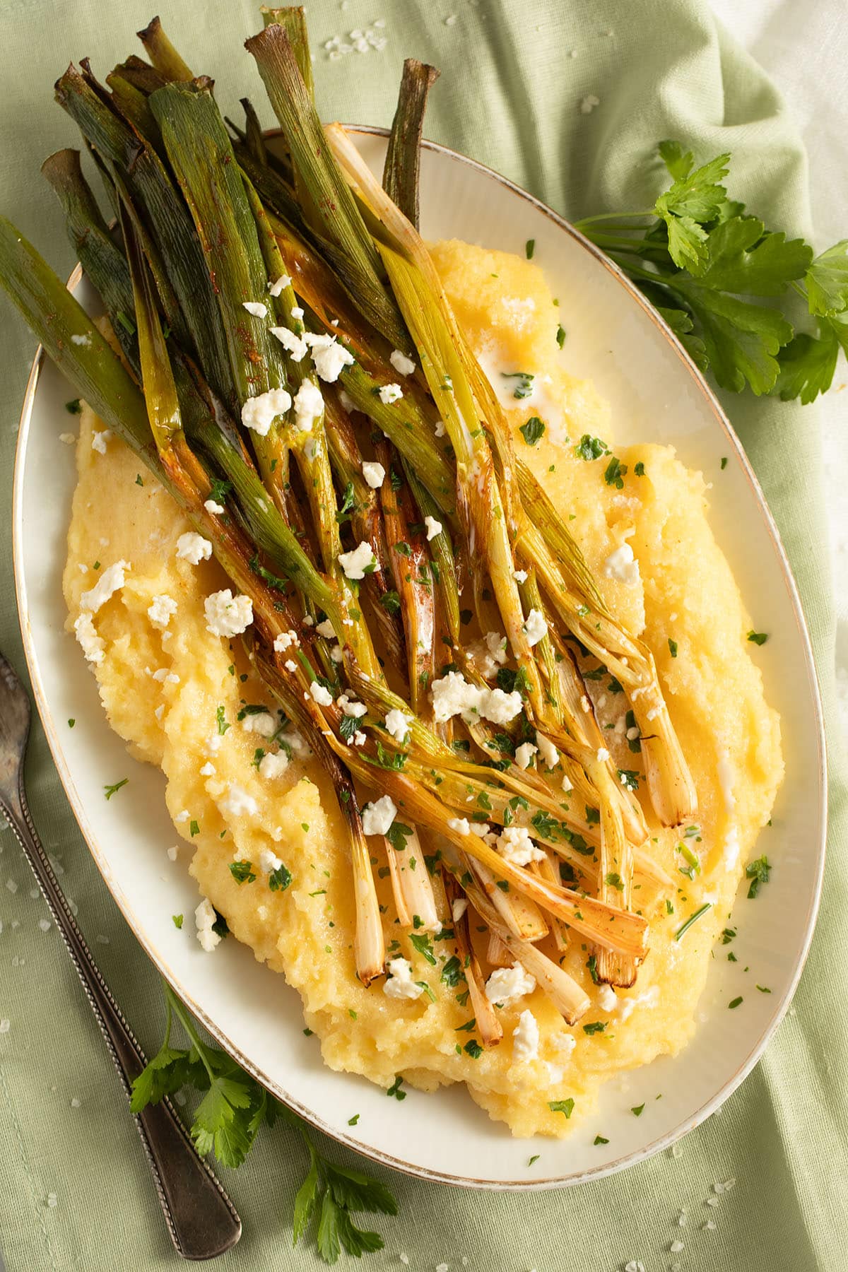 roasted scallions with cornmeal and feta cheese on a platter.