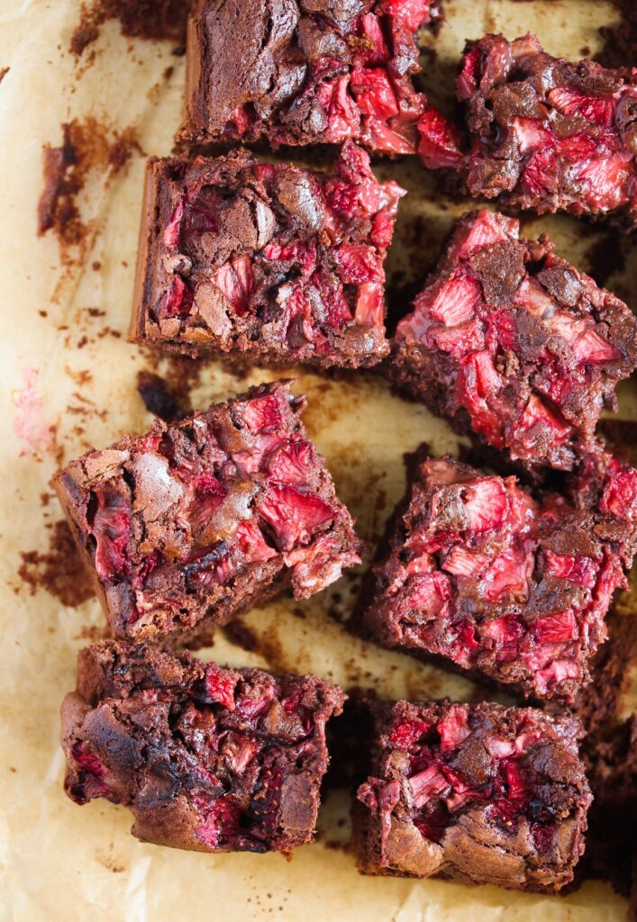 sliced brownies with strawberries on parchment paper