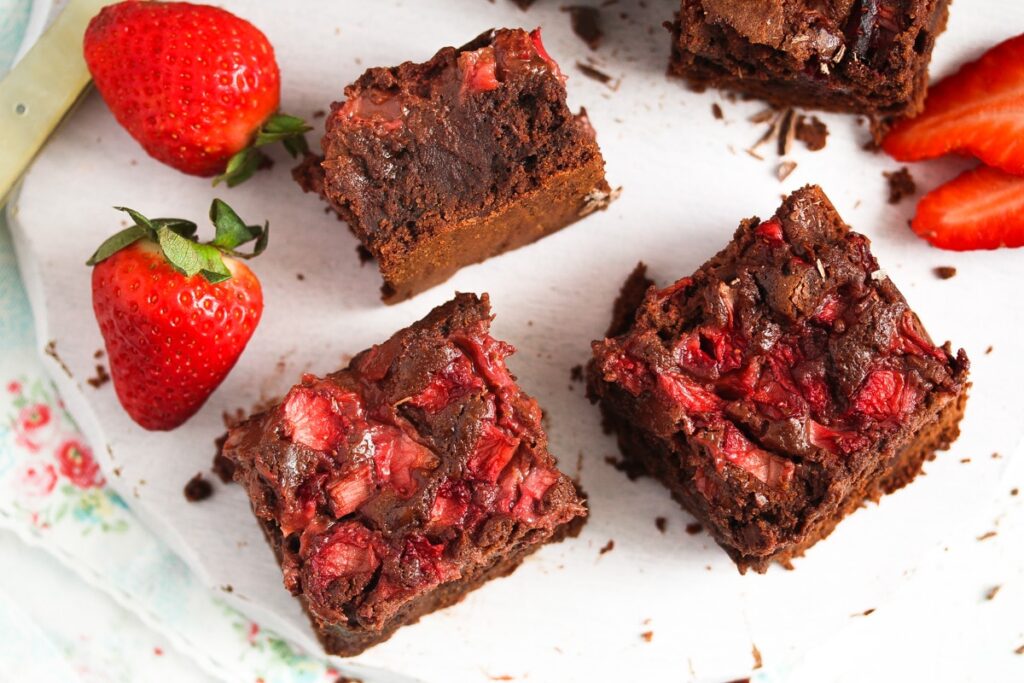 chocolate brownies with berries on a white wooden platter