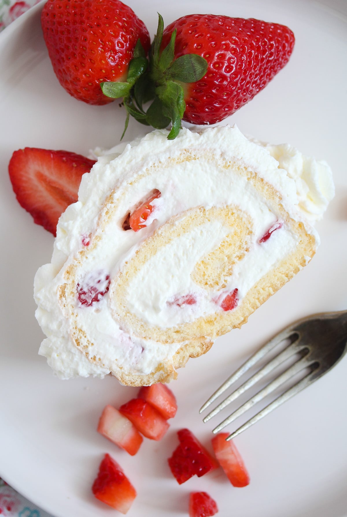 slice of cream cake with berries on a white plate with a fork