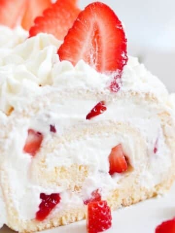 close up of a strawberry swiss roll filled with cream cheese and cream filling.
