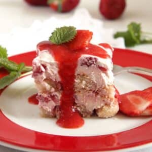 one square piece of strawberry tiramisu with strawberry sauce dripping from it.
