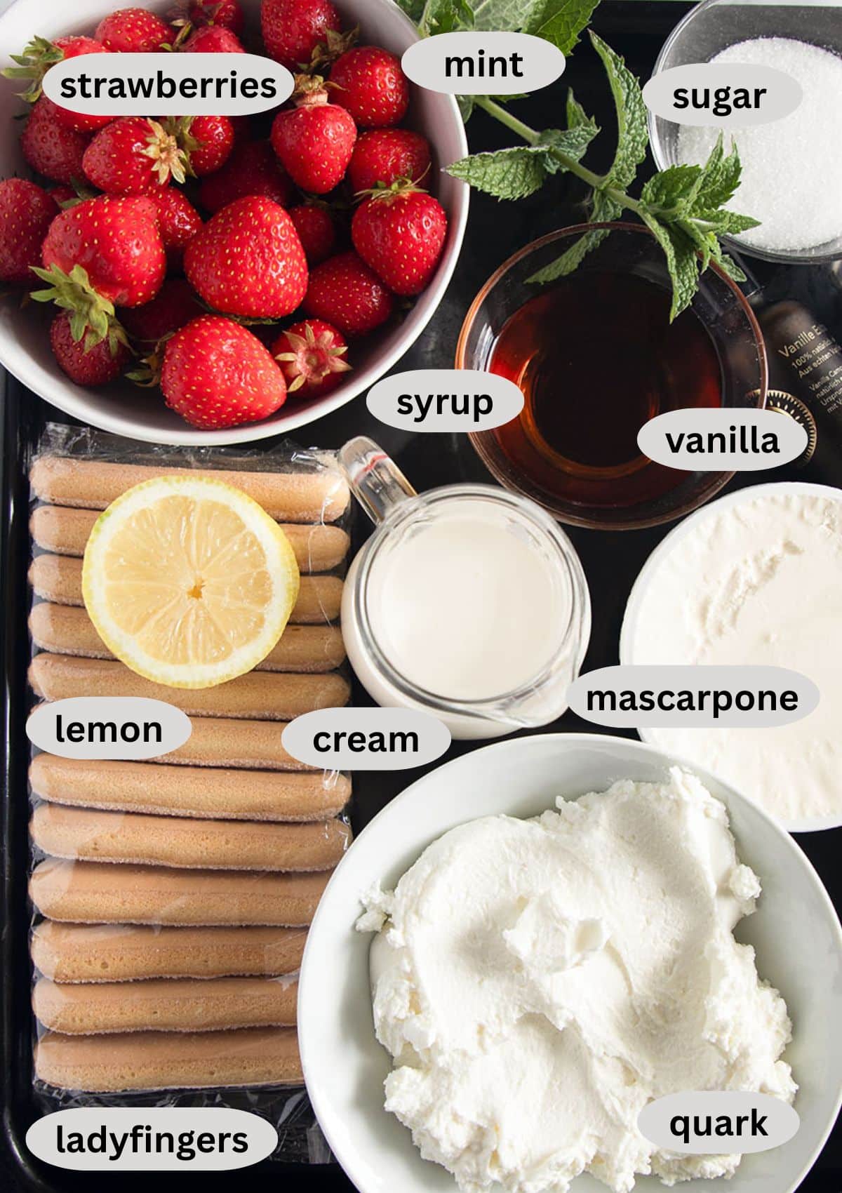 labeled ingredients for making tiramisu with strawberries, ladyfingers, quark, mascarpone, and cream.