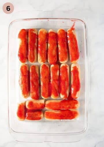 ladyfingers topped with strawberry puree for making tiramisu.
