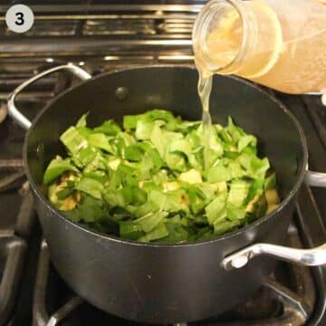 pouring stock from a bottle into pot with potatoes and wild garlic to make soup.