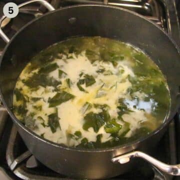 adding cream to wild garlic potato soup in a pot on the stove.