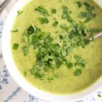 creamy green soup on a white blue tablecloth