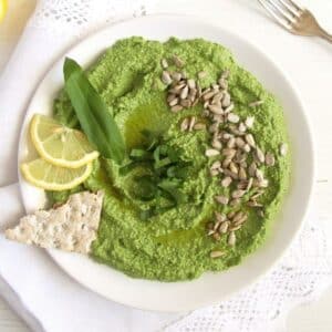 wild garlic spread or dip garnished with sunflower seeds, leaves, and lemon slices in a bowl.