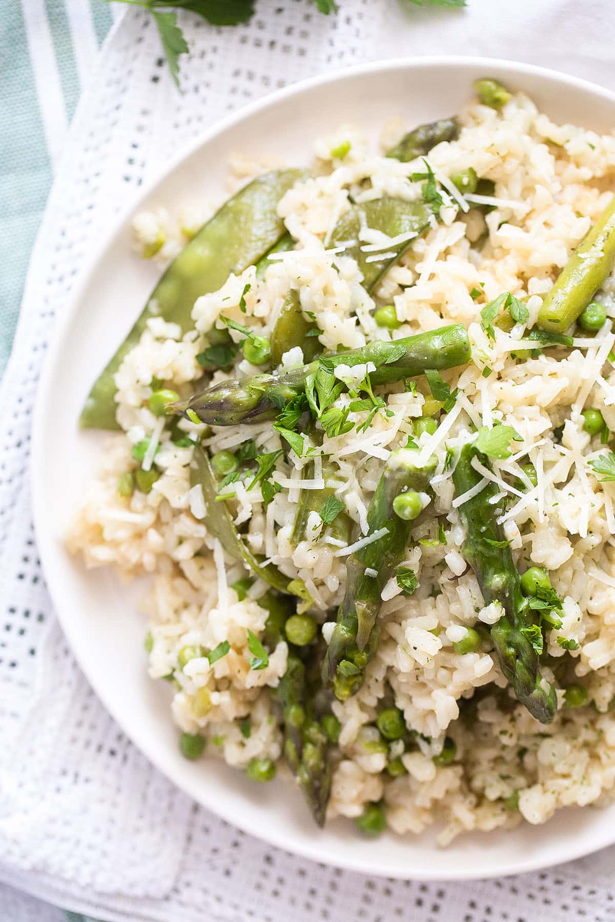 snap pea risotto with asparagus on a white plate.