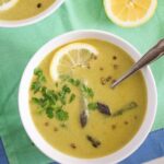 bowl of yellow soup with asparagus and lemon slices