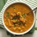 cauliflower chicken soup sprinkled with parsley in a bowl.