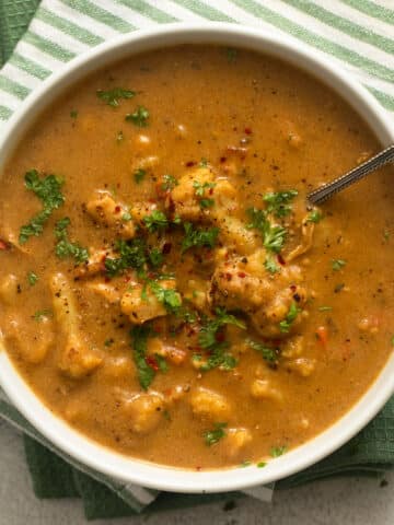 cauliflower chicken soup sprinkled with parsley in a bowl.