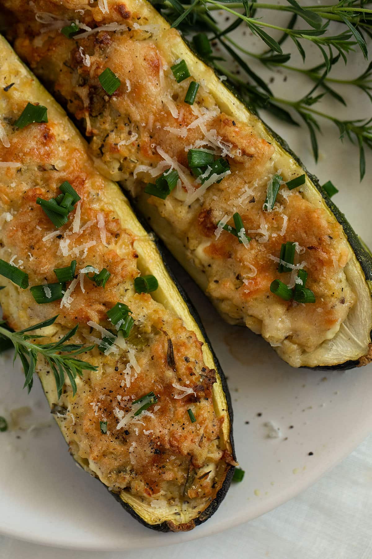 two zucchini boats filled with cottage cheese and grain on a plate.