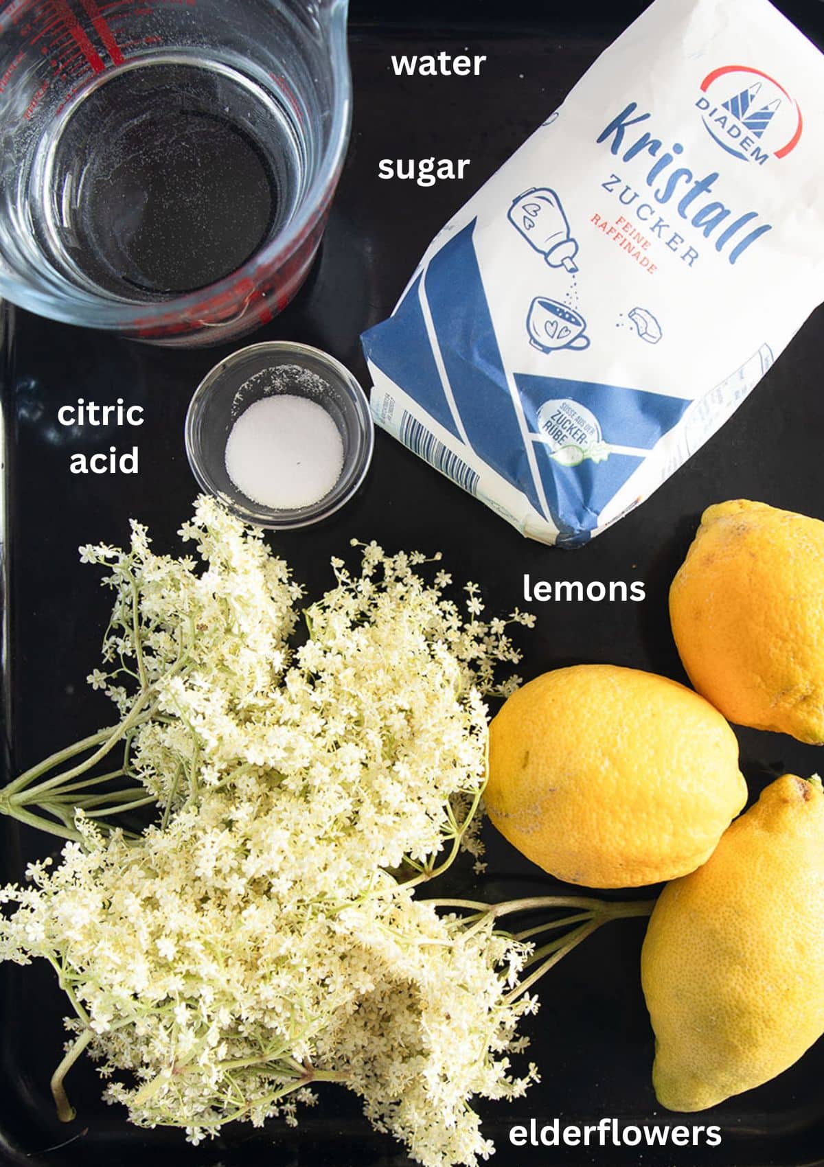 labeled ingredients for making syrup with elderflowers, lemon, sugar and citric acid.