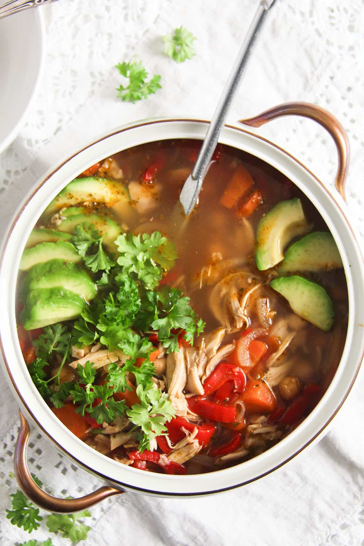 serving bowl with mexican soup with chickpeas, chicken and avocado.