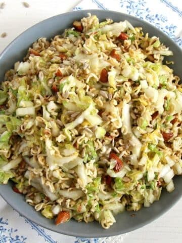 napa cabage ramen salad in a gray bowl with sunflower seeds around it.