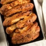 golden brown fluffy plum bread with crispy sugar topping in a loaf pan.