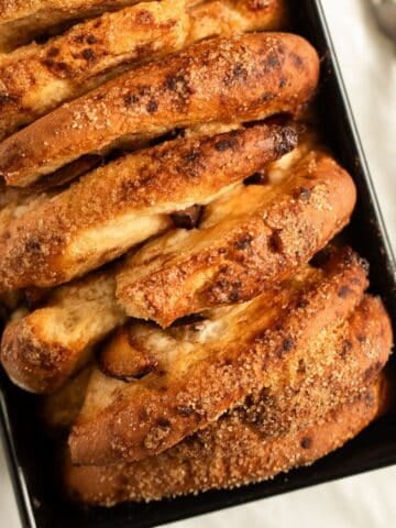 golden brown fluffy plum bread with crispy sugar topping in a loaf pan.