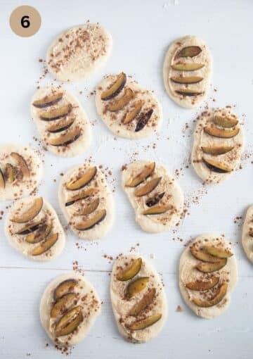many pieces of dough covered with butter sugar mixture and plum slices for making monkey bread.