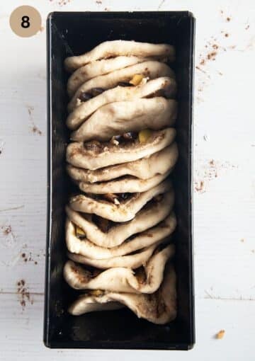 unbaked and unrisen pull apart bread with plum in a baking dish.