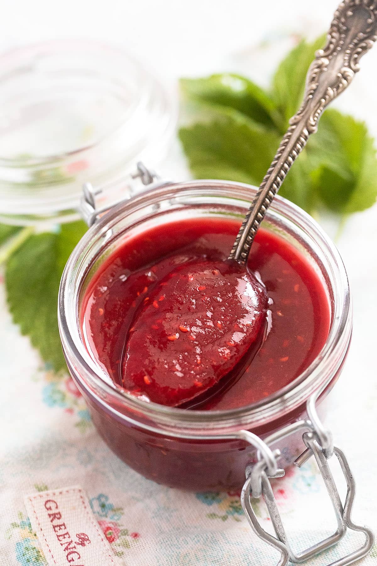 raspberry and rhubarb jam in a small jar with a spoon.