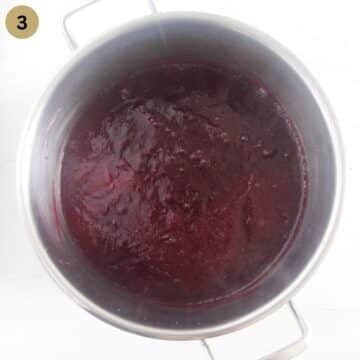 cooking jam with blueberries and rhubarb in a large pot.