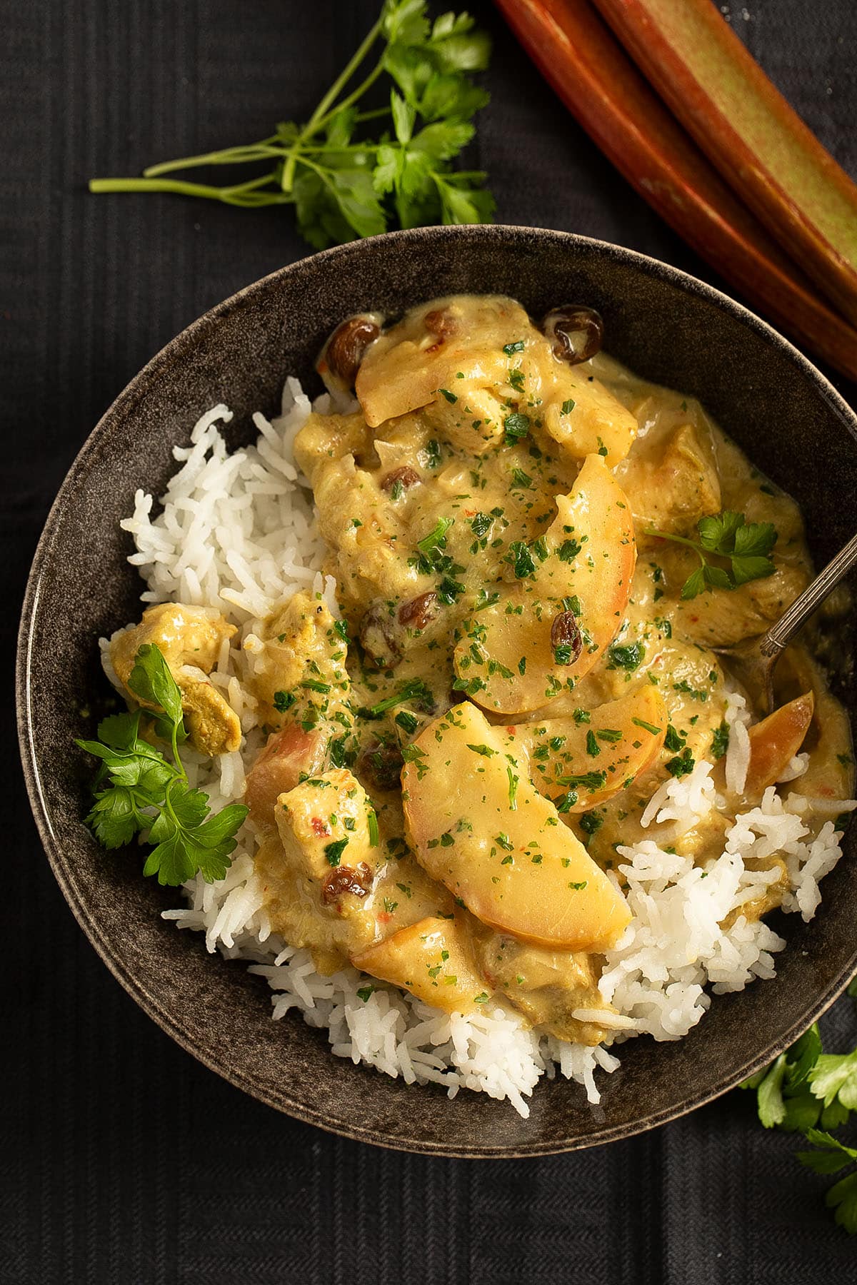 rhubarb chicken curry served over rice in a bowl.
