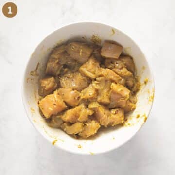 chicken breast pieces marinating with spices in a bowl.