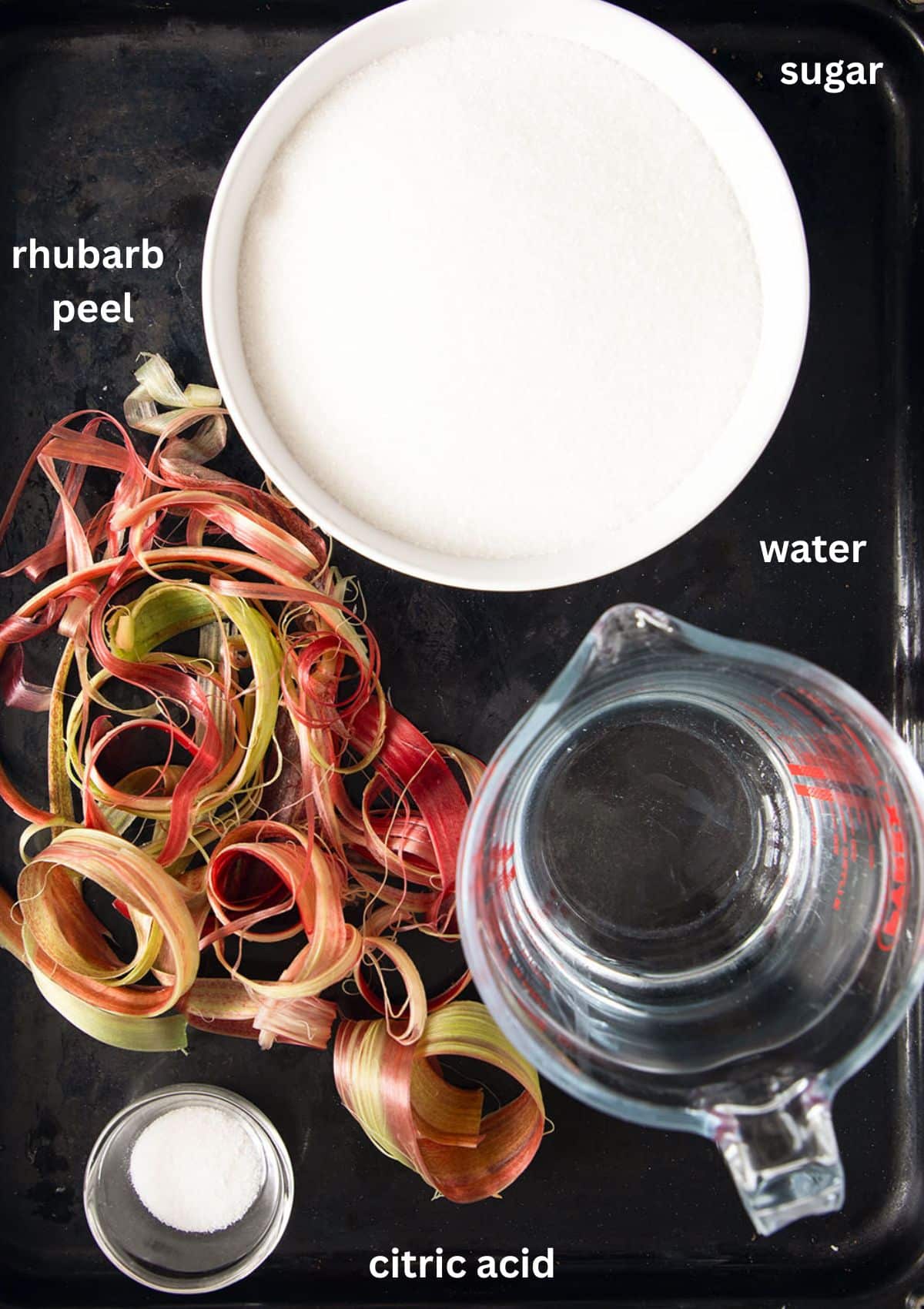 ingredients for making rhubarb syrup with rhubarb peel, sugar, water and citric acid.