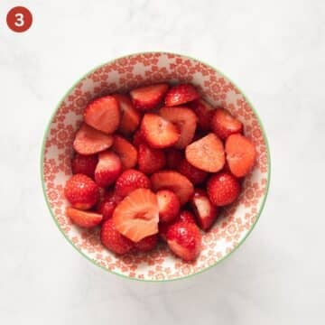 halved strawberries in a bowl.
