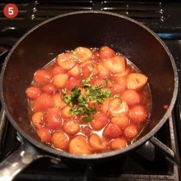 simmering strawberry sauce with chopped oregano on top.