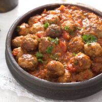 brown earthen bowl with spanish meatballs served as tapas in tomato sauce.