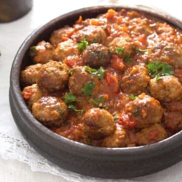 brown earthen bowl with spanish meatballs served as tapas in tomato sauce.
