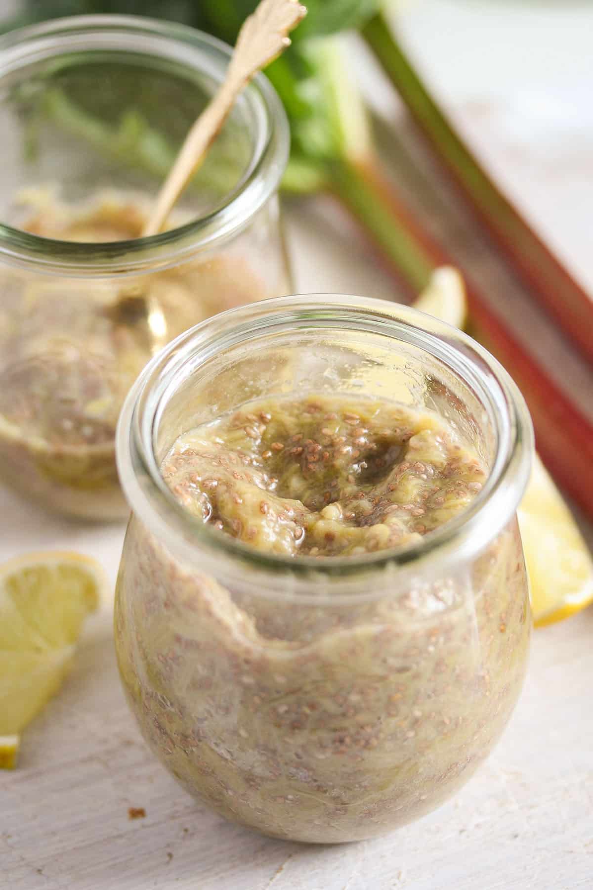 rhubarb chia jam in two jars and some rhubarb stalks beside them.